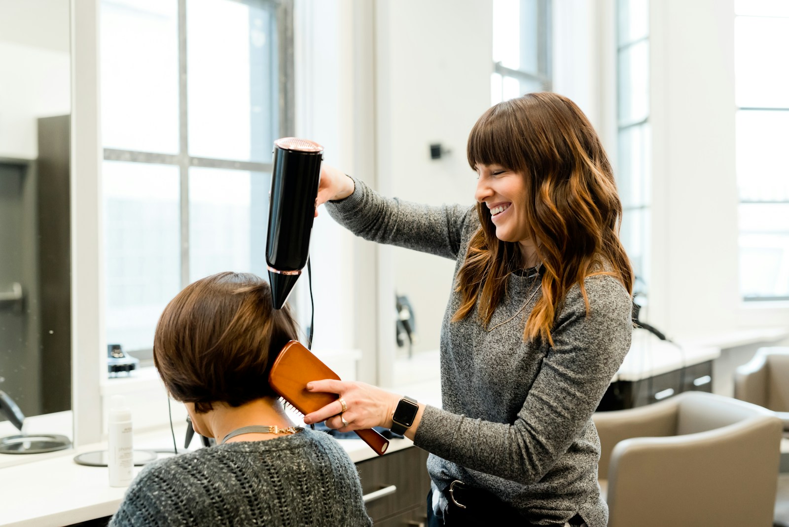 Hair stylist working on long hair in a light-filled salon